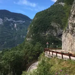 Strada panoramica sul Passo Manghen, con montagne verdi e un cielo azzurro.