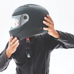 Persona indossa un casco nero, assicurandosi che sia ben saldo. È bene che il casco sia dotato di visiera per proteggere gli occhi.