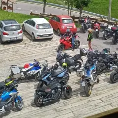 Un gruppo di motociclisti si ferma per una pausa al passo Zambla, con moto parcheggiate accanto ad alcune auto.