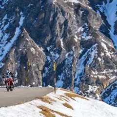 Motociclista su strada innevata tra le montagne, un viaggio da Bolzano a Livigno.