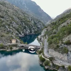 Le gole del Sagittario a Scanno, con il lago turchese, il ponte ad arco e la strada panoramica che serpeggia tra le montagne.