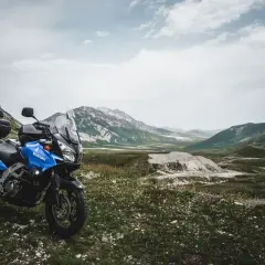Moto blu pronta per esplorare il vasto campo imperatore, con montagne maestose sullo sfondo.