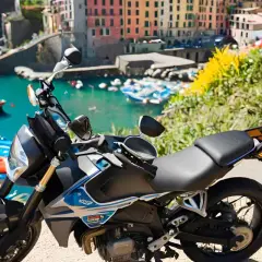 Moto parcheggiata con vista sul mare e case colorate della Liguria. Un'avventura su due ruote tra i passi liguri.