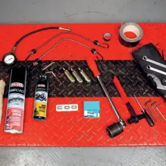 Kit di attrezzi da portare in moto: grasso catena, pulitore, chiavi, brugole, compressore portatile e nastro adesivo.