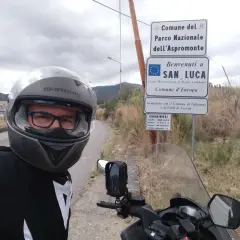 Sila in moto, selfie con casco e giacca da motociclista, vicino ai cartelli del Parco Nazionale dell'Aspromonte e di San Luca.