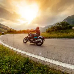Motociclista percorre una strada tortuosa in Umbria, godendosi un'avventura di 3 giorni tra paesaggi mozzafiato al tramonto.