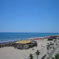 Spiaggia affollata a Metaponto, dove si trova un lido con ombrelloni, lettini e stabilimenti balneari. Il mare azzurro e il cielo limpido invitano al relax.