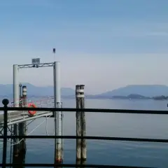 Molo di Meina, ideale per una pausa durante il giro del Lago Maggiore in moto. Montagne sullo sfondo.