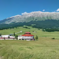 Edificio circolare con tetto rosso e montagne sullo sfondo, al passo San Leonardo.