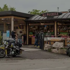 Un bar per motociclisti, "La Pacheca", con moto parcheggiate e gente che socializza all'esterno.