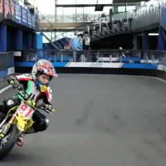 Giovane pilota in azione sul circuito del Lario, con la sua moto da corsa gialla e il numero 91 ben visibile.