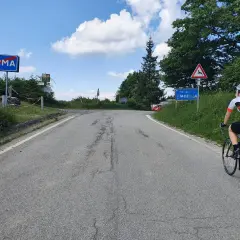 Ciclista in salita verso Piacenza, dopo aver superato il cartello di Parma. Il passo Pellizzone è un'ottima meta per gli amanti del ciclismo.