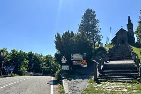 Strada e scalinata verso la chiesa in cima al passo della Cisa. Segnali indicano la via Francigena e la quota di 1041 metri.