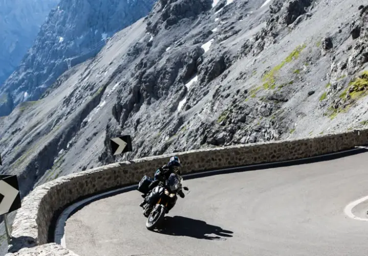 Motociclista affronta tornanti mozzafiato tra le montagne del Trentino, vicino a Merano.