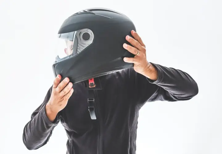 Persona indossa un casco nero, assicurandosi che sia ben saldo. È bene che il casco sia dotato di visiera per proteggere gli occhi.