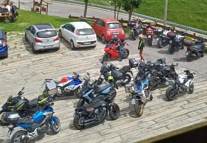 Un gruppo di motociclisti si ferma per una pausa al passo Zambla, con moto parcheggiate accanto ad alcune auto.