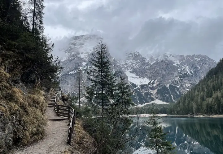 Sentiero da Brunico a Lago di Braies, con montagne innevate e riflessi sull'acqua.