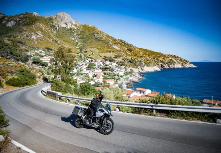 Motociclista esplora la costa dell'Isola d'Elba, tra villaggi pittoreschi e mare blu. Un'ottima idea per scoprire cosa vedere!