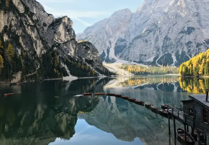Un suggestivo itinerario al Lago di Braies e dintorni, con barche di legno ormeggiate e montagne maestose riflesse nell'acqua cristallina.