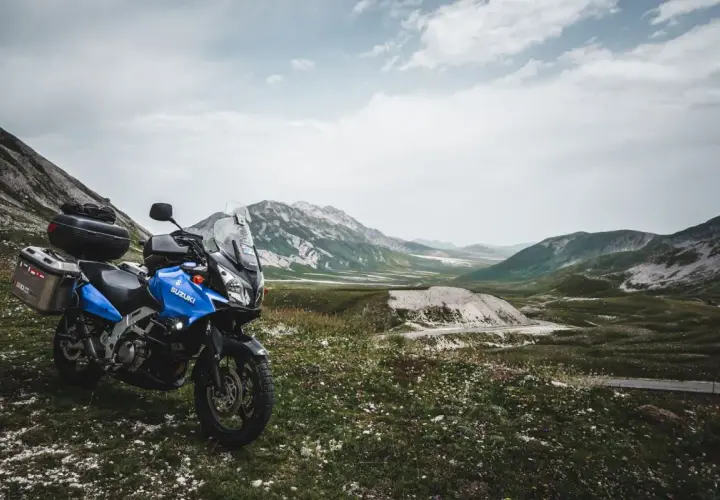 Moto blu pronta per esplorare il vasto campo imperatore, con montagne maestose sullo sfondo.