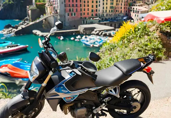 Moto parcheggiata con vista sul mare e case colorate della Liguria. Un'avventura su due ruote tra i passi liguri.