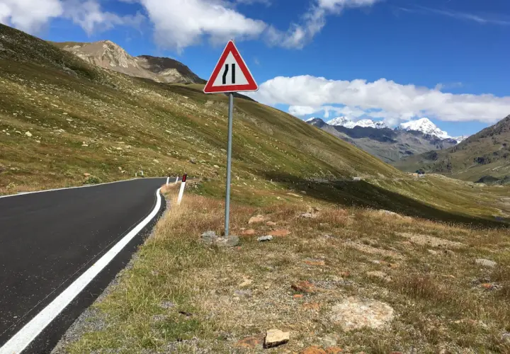 Strada di montagna con segnale di restringimento. Perfetto per sapere dove andare in moto, tra panorami mozzafiato e curve emozionanti.