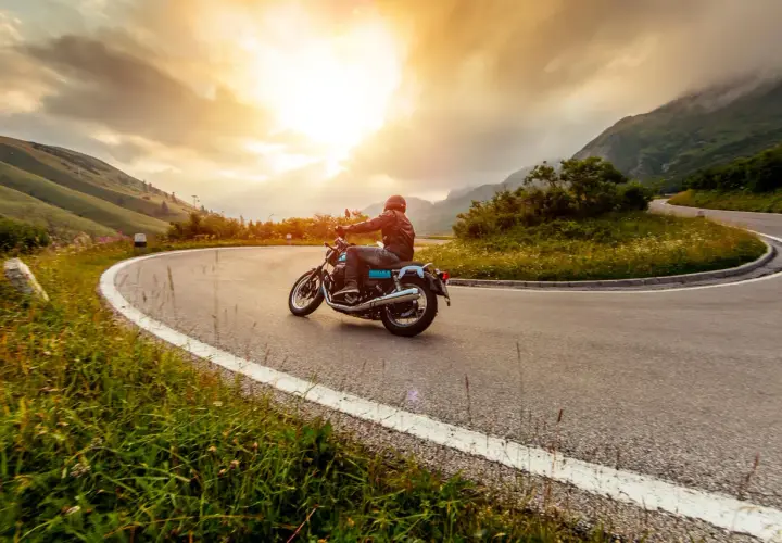 Motociclista percorre una strada tortuosa in Umbria, godendosi un'avventura di 3 giorni tra paesaggi mozzafiato al tramonto.