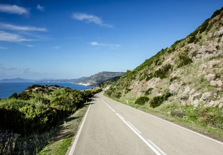 Strada panoramica lungo la costa sarda, un viaggio da Cagliari ad Alghero tra mare blu e macchia mediterranea.