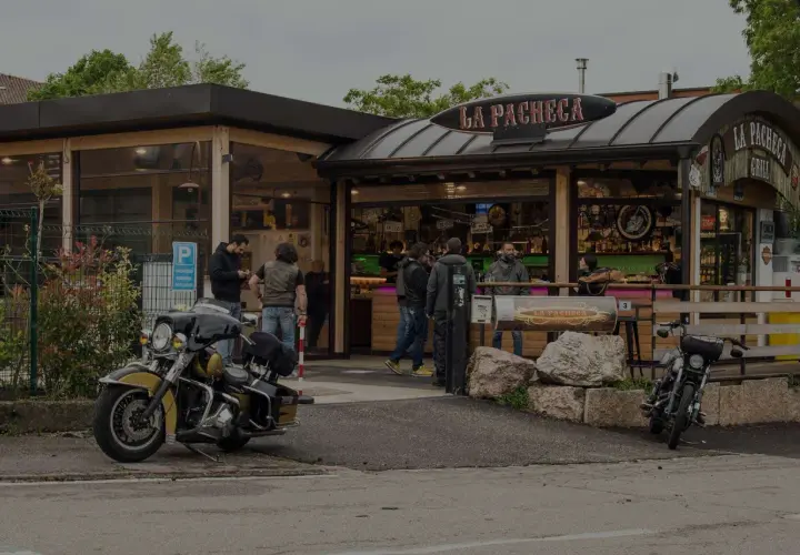 Un bar per motociclisti, "La Pacheca", con moto parcheggiate e gente che socializza all'esterno.
