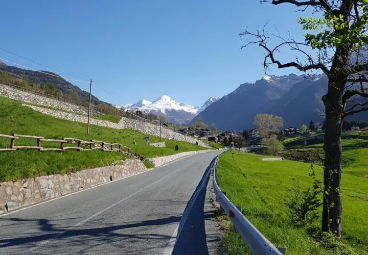 Strada panoramica verso Champoluc con montagne innevate sullo sfondo.