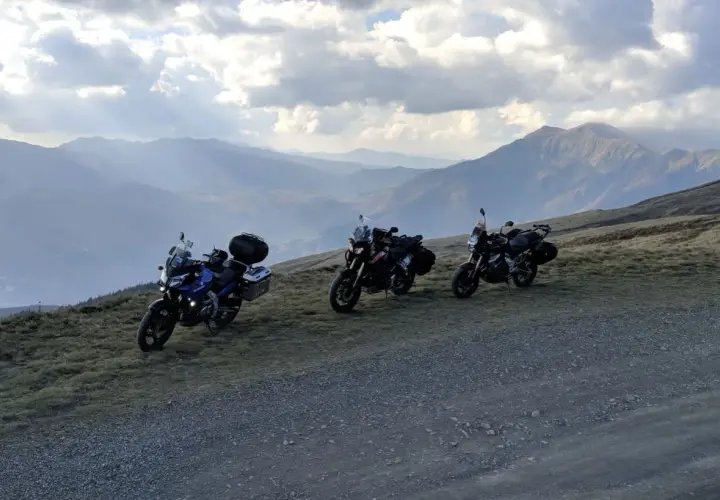 Tre moto attendono al Passo dell'Abetone, con un panorama montano mozzafiato sotto un cielo nuvoloso.