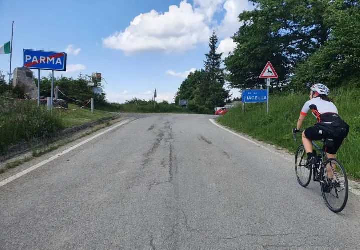 Ciclista in salita verso Piacenza, dopo aver superato il cartello di Parma. Il passo Pellizzone è un'ottima meta per gli amanti del ciclismo.