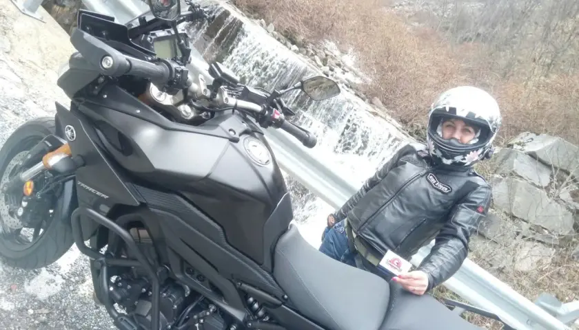Panoramica Zegna moto con motociclista in giacca di pelle, accanto a una cascata.