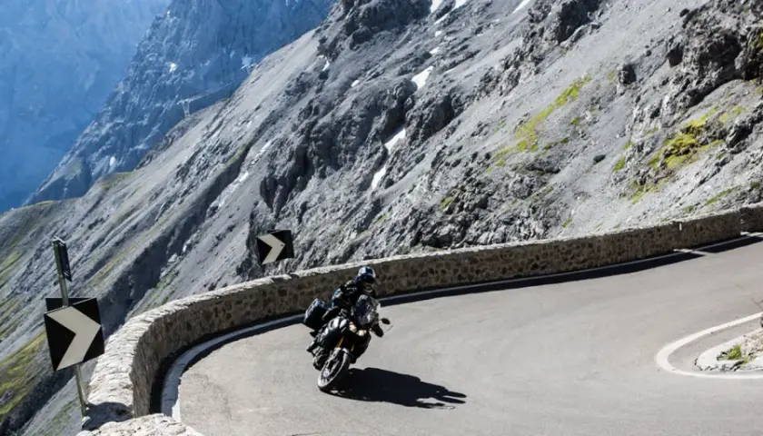 Motociclista affronta tornanti mozzafiato tra le montagne del Trentino, vicino a Merano.