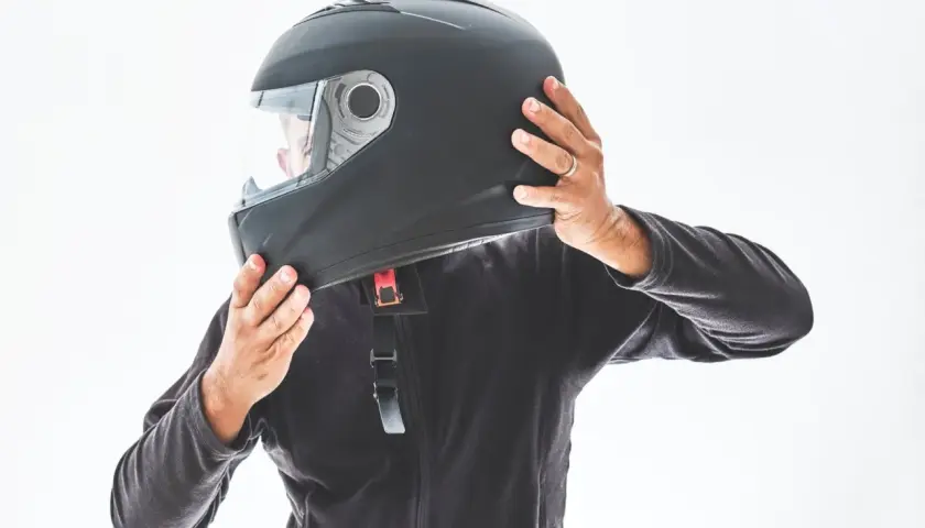 Persona indossa un casco nero, assicurandosi che sia ben saldo. È bene che il casco sia dotato di visiera per proteggere gli occhi.