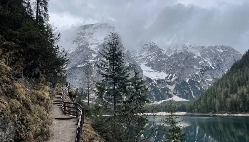 Sentiero da Brunico a Lago di Braies, con montagne innevate e riflessi sull'acqua.