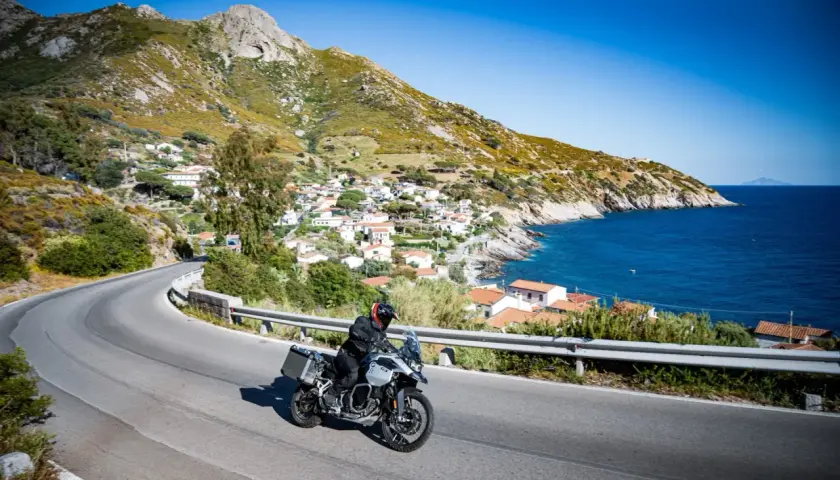 Motociclista esplora la costa dell'Isola d'Elba, tra villaggi pittoreschi e mare blu. Un'ottima idea per scoprire cosa vedere!