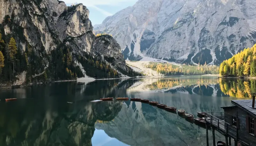 Un suggestivo itinerario al Lago di Braies e dintorni, con barche di legno ormeggiate e montagne maestose riflesse nell'acqua cristallina.