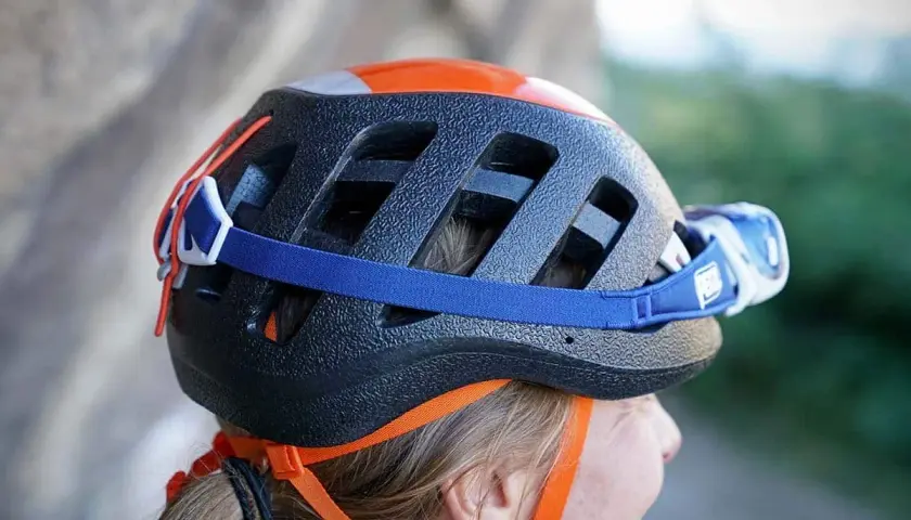 Casco da arrampicata nero con dettagli arancioni e lampada frontale. Per capire se un casco è omologato, controlla le etichette interne.