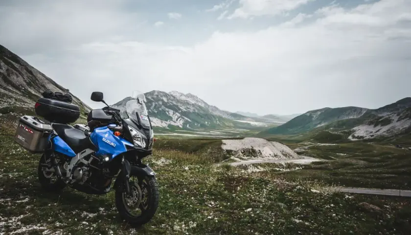 Moto blu pronta per esplorare il vasto campo imperatore, con montagne maestose sullo sfondo.