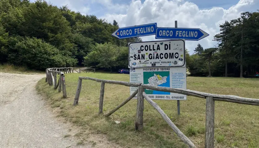Segnaletica stradale indica la direzione per Orco Feglino e la Colla di San Giacomo, immersa nel verde di una foresta.