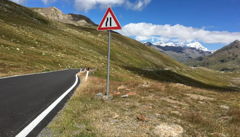 Strada di montagna con segnale di restringimento. Perfetto per sapere dove andare in moto, tra panorami mozzafiato e curve emozionanti.