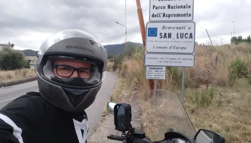 Sila in moto, selfie con casco e giacca da motociclista, vicino ai cartelli del Parco Nazionale dell'Aspromonte e di San Luca.