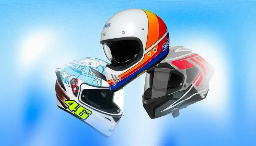 Tre caschi moto in primo piano, uno bianco con grafica retrò, uno bianco con disegno invernale e il numero 46, e uno grigio con dettagli rossi. Un test caschi moto completo.