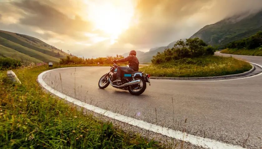 Motociclista percorre una strada tortuosa in Umbria, godendosi un'avventura di 3 giorni tra paesaggi mozzafiato al tramonto.