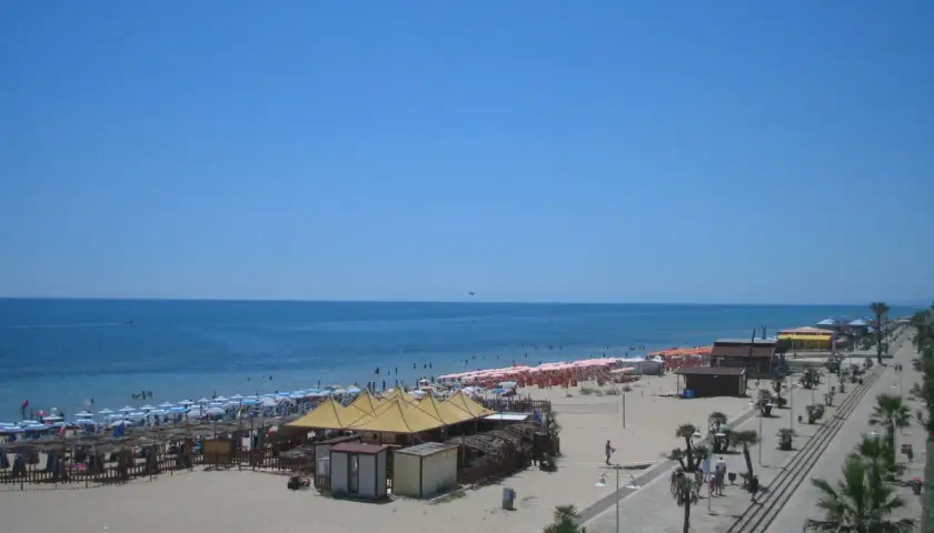 Spiaggia affollata a Metaponto, dove si trova un lido con ombrelloni, lettini e stabilimenti balneari. Il mare azzurro e il cielo limpido invitano al relax.
