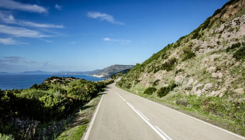 Strada panoramica lungo la costa sarda, un viaggio da Cagliari ad Alghero tra mare blu e macchia mediterranea.