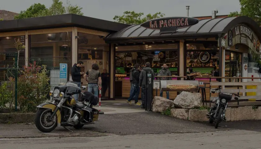 Un bar per motociclisti, "La Pacheca", con moto parcheggiate e gente che socializza all'esterno.