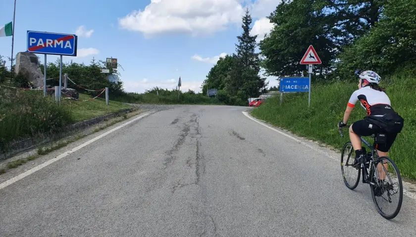 Ciclista in salita verso Piacenza, dopo aver superato il cartello di Parma. Il passo Pellizzone è un'ottima meta per gli amanti del ciclismo.