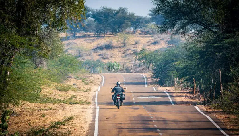 Un motociclista solitario affronta una strada tortuosa, immerso in un paesaggio arido e verdeggiante. Le sue gite in moto lo portano verso l'orizzonte.